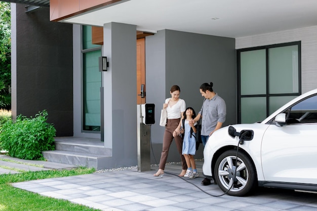 Pais jovens progressistas e filha morando em uma casa com carro elétrico