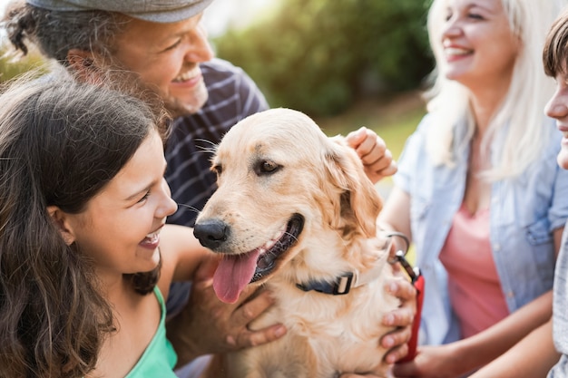 Pais jovens se divertindo com as crianças e seu animal de estimação ao ar livre no parque no verão