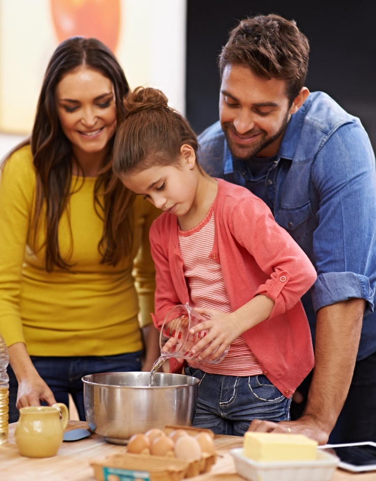 Foto pais, menina e cozinha para assar com amor, ingredientes para bolo ou sobremesa com apoio e feito à mão com cuidado, mãe, pai e filho juntos na casa da família para se unirem ou ensinarem com afeto.