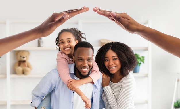 Pais negros sorridentes carregando sua filha pré-adolescente sorridente