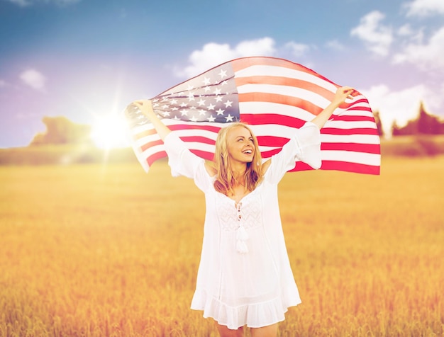 país, patriotismo, dia da independência e conceito de pessoas - jovem sorridente feliz em vestido branco com bandeira nacional americana em campo de cereais