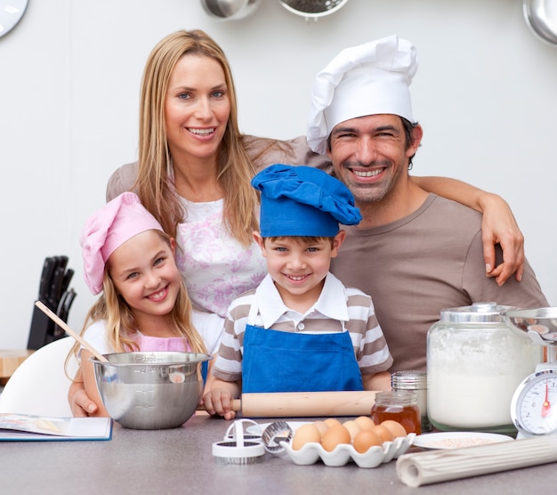 Pais sorridentes ajudando as crianças a assar na cozinha