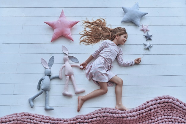 Foto en el país de los sueños. vista superior de la niña linda manteniendo los ojos cerrados y sonriendo