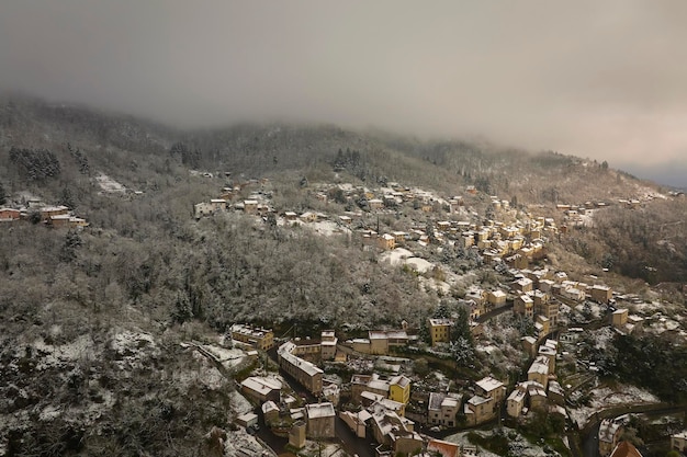 Paisagem aérea de inverno do centro histórico denso da cidade de thiers na região de auvergnerhonealpes do departamento de puydedome na frança telhados de edifícios antigos e ruas estreitas na queda de neve