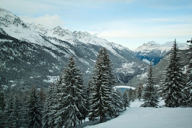 Paisagem alpina do inverno com montanhas nevadas, floresta e lago congelado azul, Chamonix, França