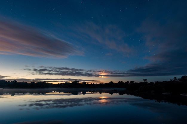 Paisagem ao amanhecer com lua entre nuvens em Los Barruecos