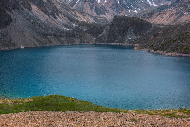 Paisagem atmosférica com ondulações na superfície da água do lago de montanha profunda de cor azul fantasma entre rochas afiadas e montanhas altas Maravilhosa vista dramática para o lago de montanha azul profundo e penhasco rochoso