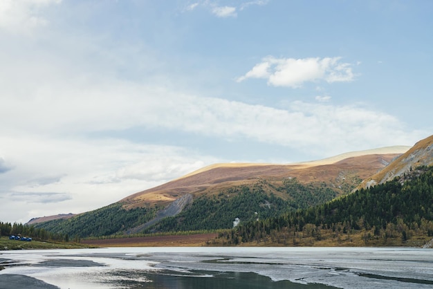 Paisagem cênica de outono com lago de montanha e montanhas heterogêneas com floresta. Vista alpina colorida para o lago raso e grandes colinas multicoloridas em cores de outono. Belas paisagens montanhosas vivas no outono.