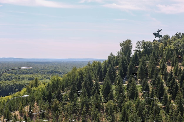 Paisagem com árvores e montanhas com o monumento de um cavaleiro no topo em Ufa Rússia