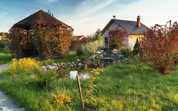 Paisagem com jardim lagoa e pequena cabana no campo. Cena rural.