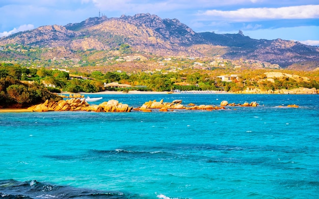 Paisagem com manhã romântica na praia de Capriccioli na Costa Esmeralda do mar Mediterrâneo na ilha da Sardenha, na Itália. Céu com nuvens. Província de Porto Cervo e Olbia. Mídia mista.