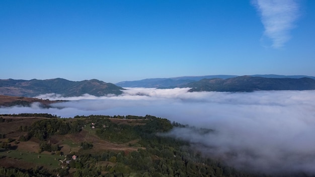 Paisagem com montanhas e nuvens cobrindo vale, vista panorâmica na natureza.