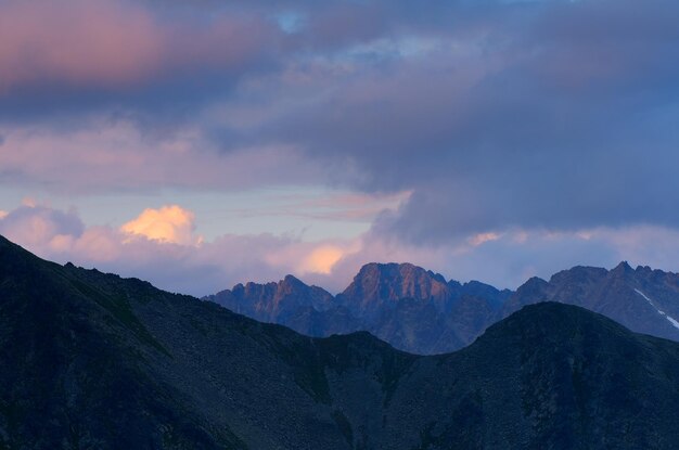 Paisagem com nuvens e picos de montanhas ao pôr do sol