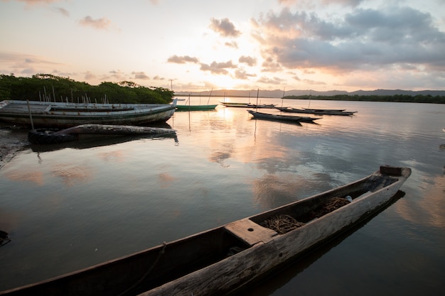 Paisagem com pôr do sol com canoas de pesca na beira do rio.