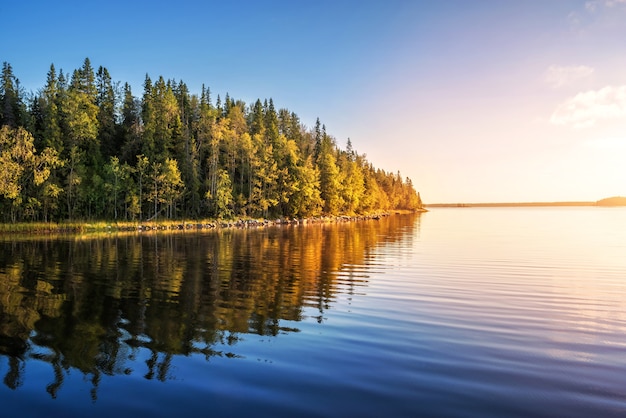 Paisagem com um lago e o reflexo das árvores sob os raios do sol da manhã nas Ilhas Solovetsky