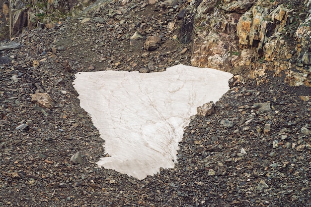 Paisagem com um pequeno campo de neve em talude em uma montanha rochosa