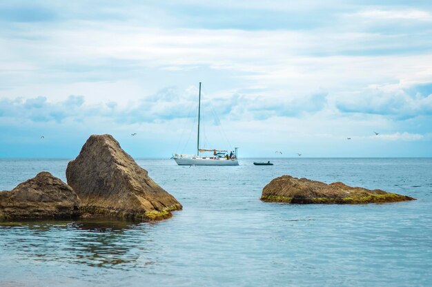 Paisagem com um veleiro no mar entre grandes pedras Viagem de verão Férias à beira-mar