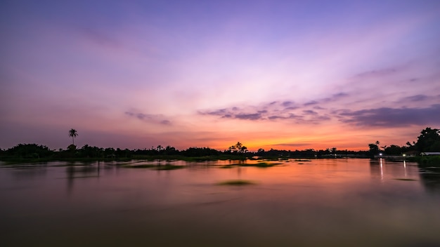 Paisagem crepuscular à beira do rio e longas exposições de silhueta de árvores filmadas na tailândia