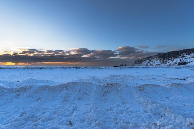 Paisagem da área da praia Praia de areia preta totalmente coberta de neve com nascer do sol dourado