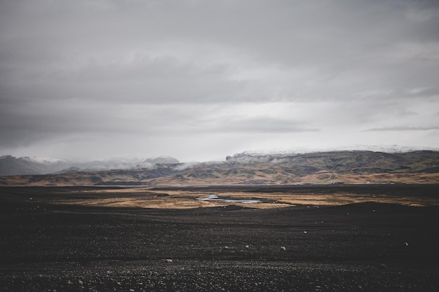 Foto paisagem da islândia com solo preto e marrom em um planalto com montanhas e geleiras ao fundo