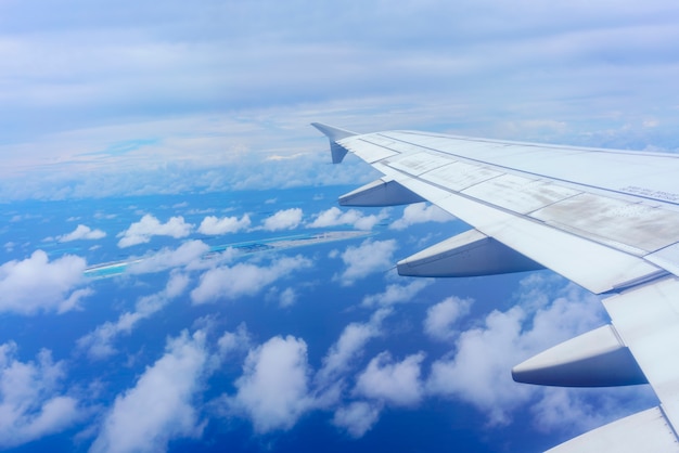 Paisagem da janela do avião vendo a asa do avião nuvens brancas céu azul Ilhas Maldivas