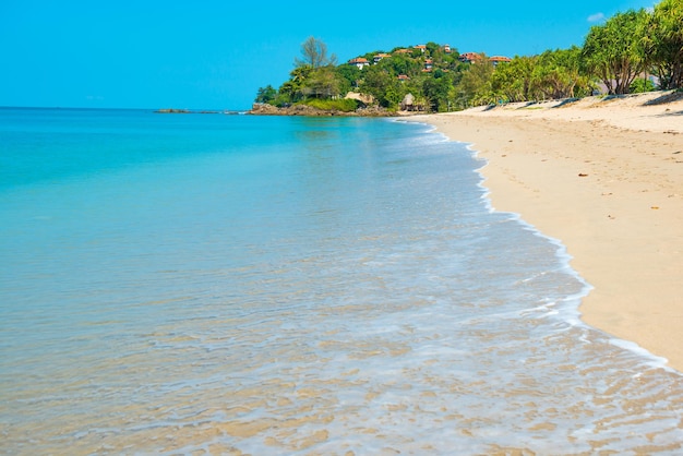 Paisagem da longa praia de areia, mar claro e árvores verdes na ilha tropical