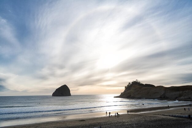 Paisagem da praia de canhão, oregon, EUA. dia nublado ensolarado. férias de verão. pessoas caminhando na praia com água do mar ou oceano. natureza da paisagem marinha.