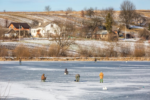 Paisagem da Ucrânia. As pessoas estão pescando em um lago congelado na aldeia de Svirzh Ucrânia