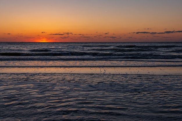 Paisagem de ardência bonita do por do sol no mar negro e no céu alaranjado acima dela com reflexão dourada do sol impressionante em ondas calmas como a. incrível vista por do sol de verão na praia. natureza russa, sochi