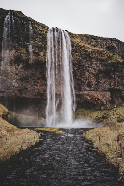 Foto paisagem de cachoeira na islândia em outubro com cores verdes marrons e terra preta