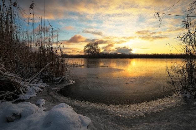 Paisagem de inverno com rio congelado e céu ao pôr do sol