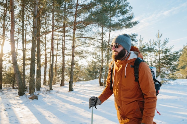 Paisagem de inverno um homem com uma mochila e roupas quentes de inverno na floresta viajando nas montanhas