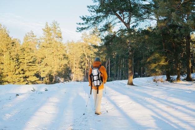 Paisagem de inverno um homem com uma mochila e roupas quentes de inverno na floresta viajando nas montanhas