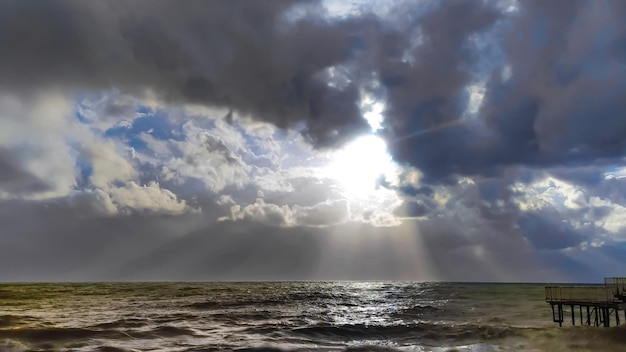 Paisagem de mar tempestuoso e nuvens com lacunas raios de sol vista da costa
