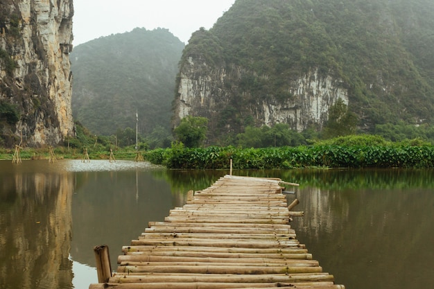 Paisagem de montanha com uma ponte de madeira e lago, NinhBinh, panorama vietnamita em Trang An