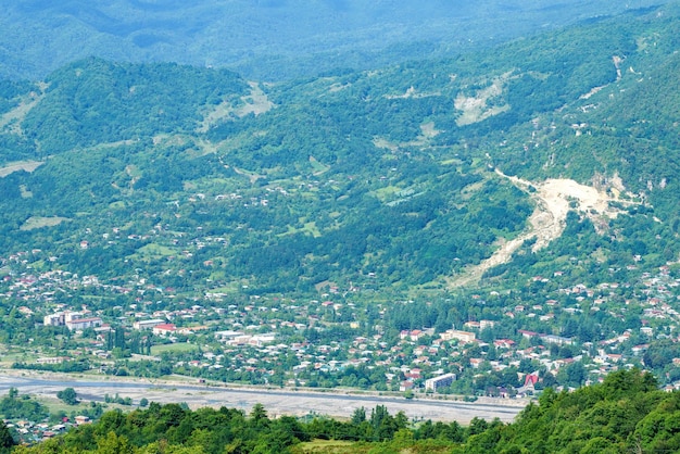 Paisagem de montanha georgiana com uma estrada rural vista da aldeia e um rio de montanha