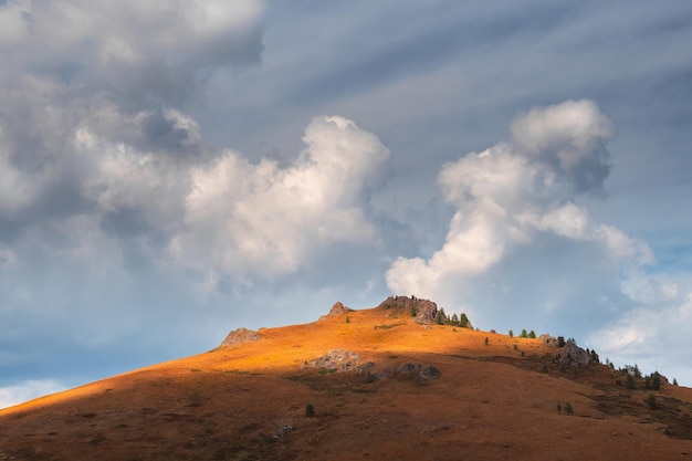 Paisagem de montanha incrível com rocha de cone na luz do sol dourada sob belas nuvens brancas fundo de natureza da montanha rochosa e floresta de cedro verde pano de fundo ensolarado colorido com alta montanha rochosa