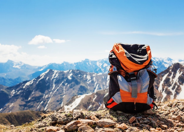 Paisagem de montanha nevada. a mochila do turista fica sobre as rochas no topo das montanhas.