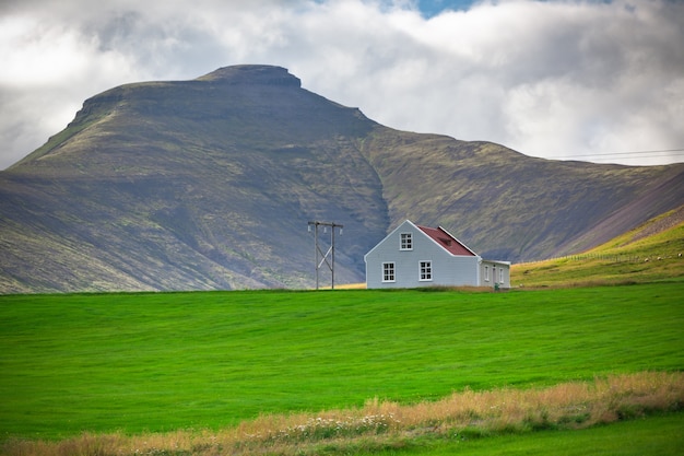 Paisagem de montanhas com uma casa islandesa de white siding