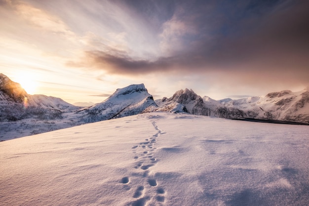 Paisagem de montanhas de neve com pegada na neve ao nascer do sol