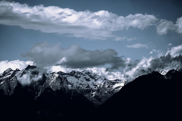 Paisagem de montanhas rochosas cobertas de neve sob um céu nublado escuro