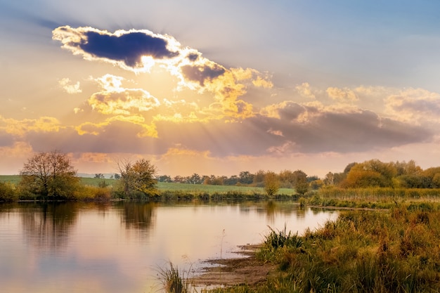 Paisagem de outono com céu pitoresco sobre o rio durante o pôr do sol, reflexo do céu no rio