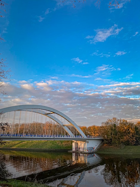 Foto paisagem de outono com ponte sobre o rio e céu azul com nuvens