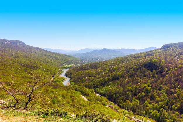 Paisagem de primavera com vista para colinas florestais e um rio no sopé do cáucaso