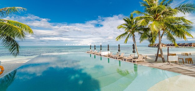 Paisagem de turismo ao ar livre Resort de praia de luxo com piscina e cadeiras de praia ou espreguiçadeiras sob guarda-chuvas com palmeiras e céu azul Conceito de fundo de viagens e férias de verão