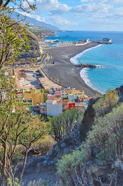 Paisagem de uma costa oceânica com areia preta da praia em Puerto de Tazacorte Casas de cidade coloridas ou acomodações de estância de férias perto da beira-mar em um belo destino turístico La Palma Espanha