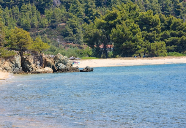 Paisagem de verão da costa do mar Egeu com praia de areia (Sithonia, Halkidiki, Grécia). Pessoas irreconhecíveis.