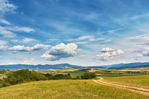 Foto paisagem de verão da eslováquia campos verdes de verão prados colinas das montanhas tatra viajar em férias estrada rural na região de spis eslováchia parque nacional de spissky hrad em fundo