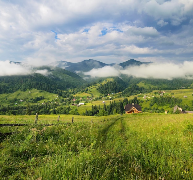 Paisagem de verão das montanhas dos Cárpatos com colinas verdes e casa de madeira, fundo incrível vintage hipster