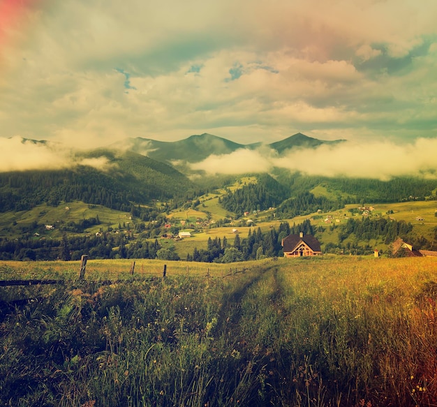 Paisagem de verão das montanhas dos Cárpatos com colinas verdes e fundo incrível de hipster vintage de casa de madeira